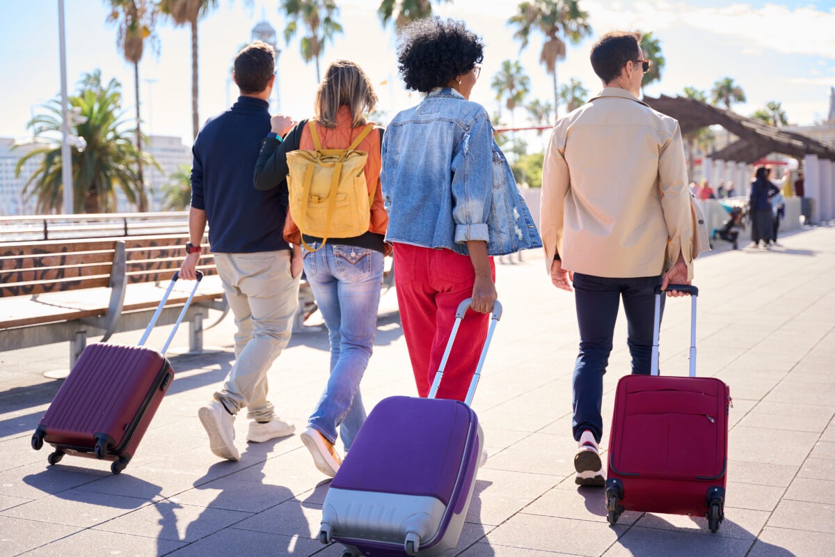 Back view of a group of unrecognizable people walking with their luggage